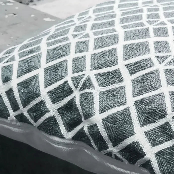 Close-up view of a grey pillow showing the woven white diamond pattern texture