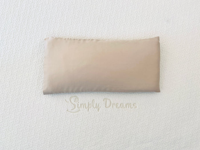 beige-colored baby pillowcase shown on a white textured mattress with the Simply Dreams logo.