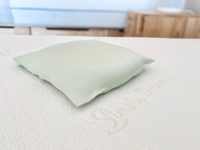 Simply Dreams sage green organic bamboo lyocell baby head-shaping pillowcase resting on a white mattress