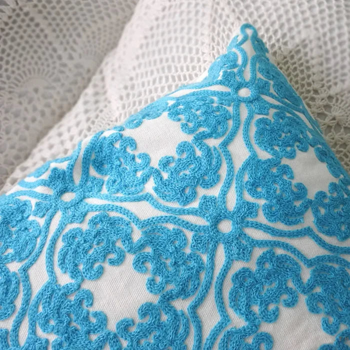 Close-up view of the intricate blue embroidered pattern on a white pillow