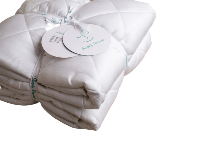 Close-up of folded white quilted fabric with a 'Simply Dreams' brand tag attached.